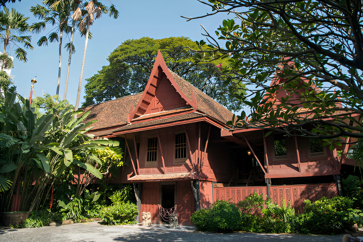 Teakwood Jim Thompson House exterior in Bangkok, Thailand, with lush green gardens.